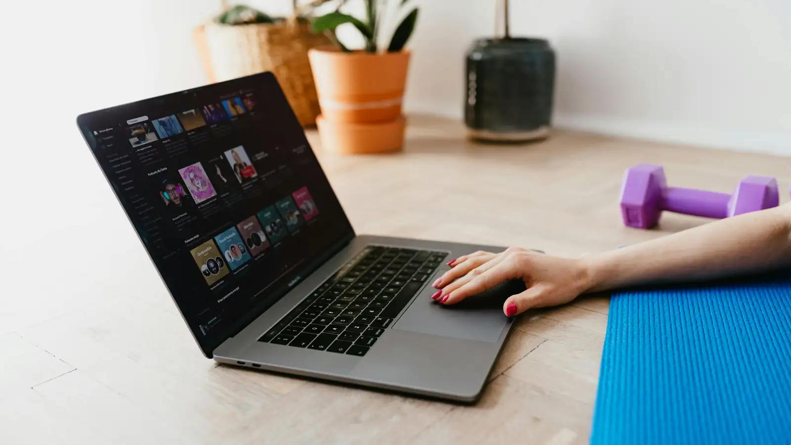 Woman doing strength workout at home following online coach on laptop